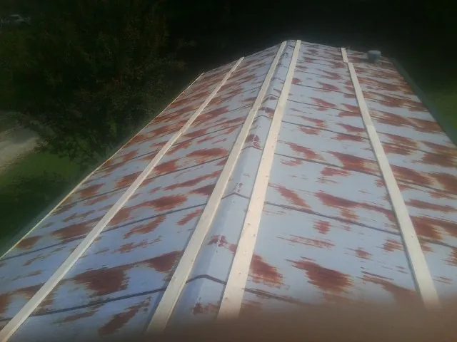 Rusted metal roof panels with new wood purlins before replacement in Linwood