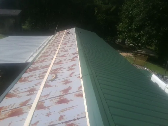 Old rusted panels beside newly installed green metal roofing — Wind Damage Roof Repair by Roofing Brothers in Linwood